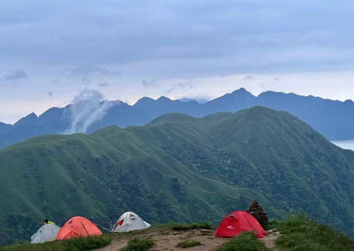 山脊上的帐篷与层叠的绿色山峦