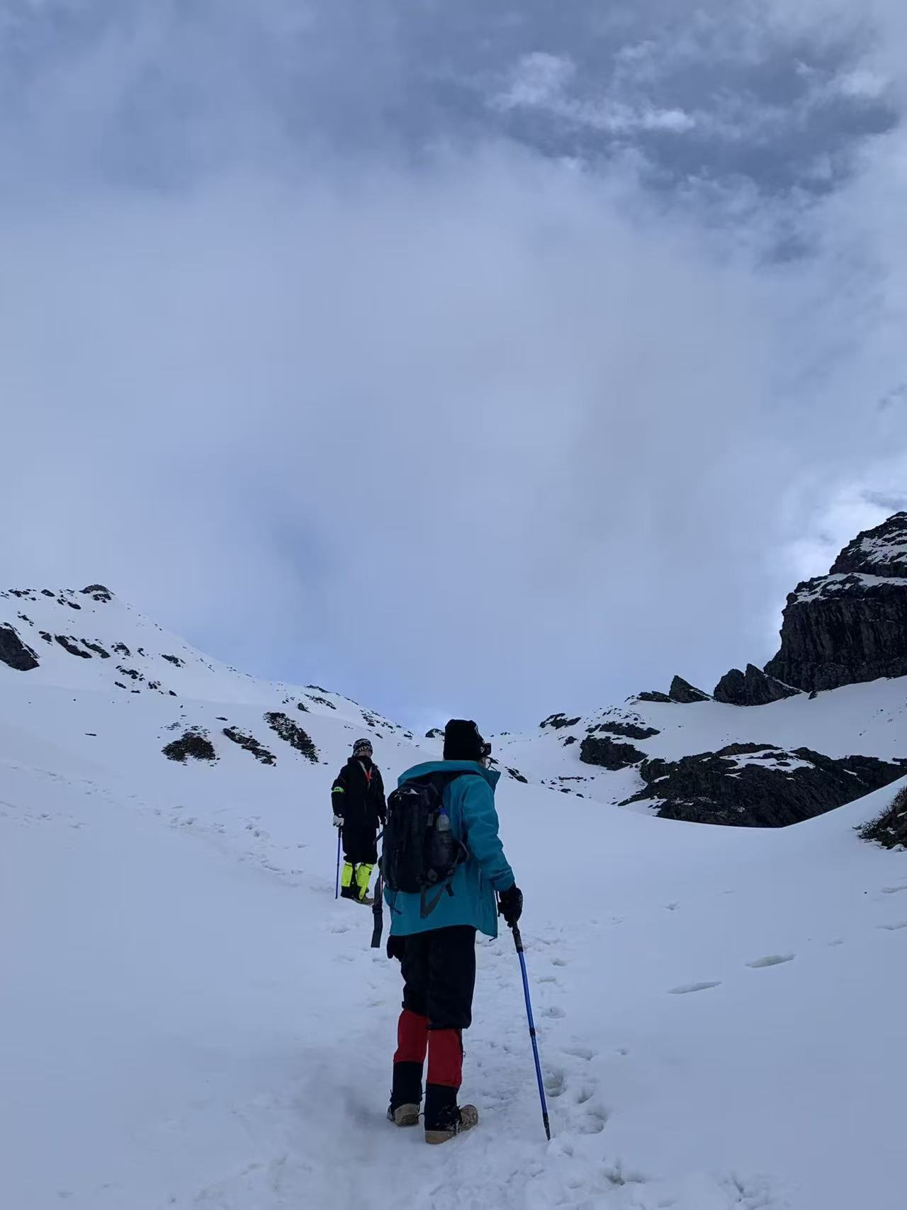 徒步者沿着雪山山谷前行